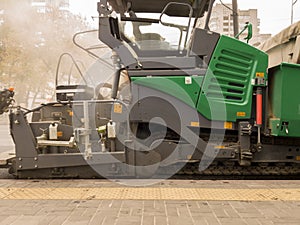 Tracked paver. Industrial pavement truck laying fresh asphalt on construction site. Asphalt a new on the road texture and a