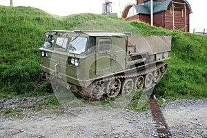 tracked tractor. old military crawler tractor all-terrain vehicle near dirt road on background of green grass