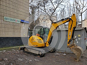 Trackhoe excavator JCB 8055 RTC with dirty scoop. Yellow tractor in urban environment