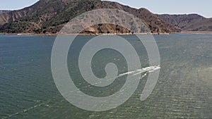 Tracking Aerial shot, motorboat that speeding on a lake, bright sunny daylight