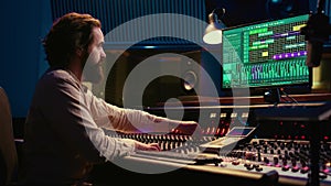 Tracking engineer editing music by adding sound effects in control room
