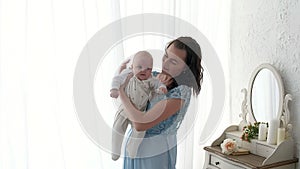 Tracking mother putting baby to sleep while walking . Attractive woman holding baby in hands and walk across living room