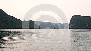 Tracking panning shot from cruise boat sailing through the limestone islands of Ha Long Bay Vietnam in