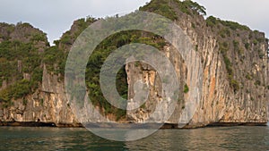 Tracking panning shot from cruise boat sailing through the limestone islands in UNESCO World Heritage site, Ha Long Bay, Vietnam