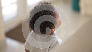 Tracking shot cute African American toddler boy walking in kitchen at home having fun smiling clapping looking at camera