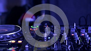 Tracking shot of a Man DJ playing with mixer and digital turntables. CDJ turntables with wires, button and sliders being