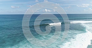 Tracking shot over surfers catching waves or surf on surfing at wild tropical ocean blue water. practicing and having