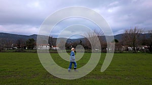 Tracking shot of a woman walking in the green fields