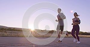 Tracking slow motion shot of sportive couple jogging outdoors in the morning, trail running experience in nature