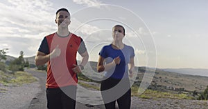 Tracking slow motion shot of sportive couple jogging outdoors in the morning, trail running experience in nature