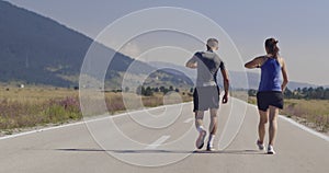 Tracking slow motion shot of sportive couple jogging outdoors in the morning, trail running experience in nature