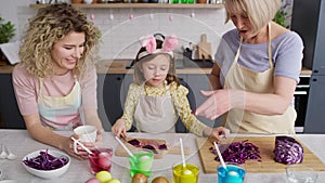 Tracking video of three generations of women in the kitchen.