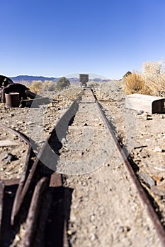 Tracks leading to an ore cart in the desert far away in perspective