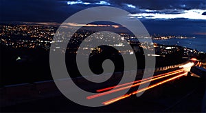 Tracks of red and white lights due to traffic by night in front of Beirut cityscape by night