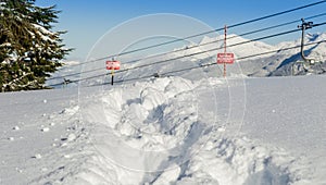 Tracks in the snow beside a ski area boundary sign.