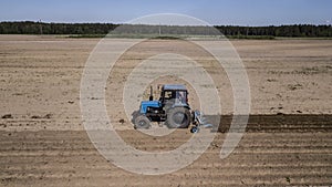 Tractor - aerial view of a tractor at work - cultivating a field in spring with blue sky - agricultural machinery