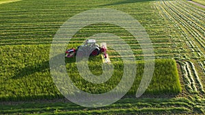 Tractor agriculture machinery harvesting herbs in a green agricultural field.