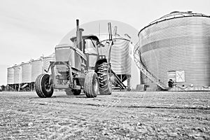 A tractor backed up to grain bins with an