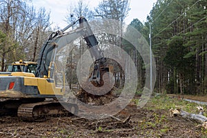 A tractor backhoe was used to remove stump roots from trees that were cut down to make way for the construction of a