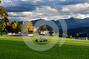 Tractor with a bale wrapper preparing to wrap a hay bale. Village Obermillstatt, Carinthia, Austria