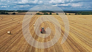 A tractor with a baler collects straw into bales.
