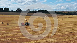 A tractor with a baler collects straw into bales.