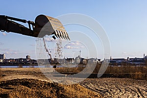 Tractor the bucket dumps the sand on the construction site photo