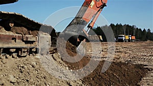 Tractor bucket is scooping the earth and sand.