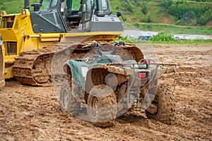 Tractor bulldozer and the ATV is parked in the mud