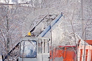 Tractor cleaning the road from the snow. Excavator cleans the streets of large amounts of snow in city. Workers sweep snow from ro