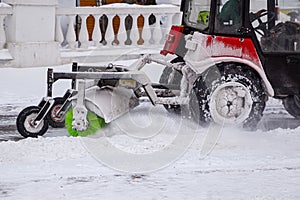 Tractor cleaning snow at city street and a parking lot after snowfall