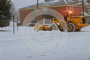 Tractor cleaning snow at street and a parking lot after snowfall