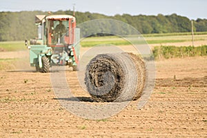 A tractor cleans the field with flax and makes bales