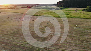 Tractor collecting hay bales. Aerial footage of farmer & haystacks