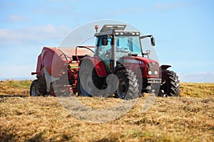 Tractor collecting haystack in the field