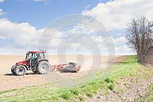 Tractor compresses the soil after planting with rollers.