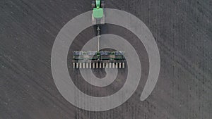 Tractor cultivating arable land for seeding crops, aerial view on modern agriculture machinery at field