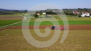 Tractor cultivating land on a field in a spring - aerial view of a farmer in early spring