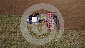 Tractor cultivating land on a field in a spring - aerial view of a farmer in early spring