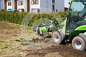 The tractor is cultivating the soil in the farm field. Freeing milling earth ground from old crops.