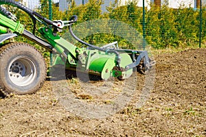 The tractor is cultivating the soil in the farm field. Freeing milling earth ground from old crops.