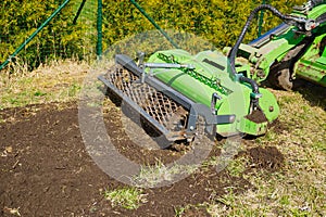 The tractor is cultivating the soil in the farm field. Freeing milling earth ground from old crops.