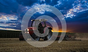 Tractor cultivating wheat stubble field at sunset, crop residue