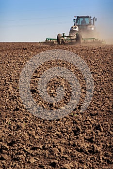 Tractor cultivator raises great dust on soil