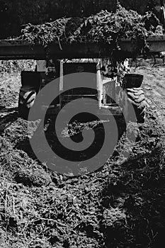 A tractor doing land leveling by a private cottage. Black and white