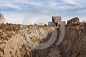 Tractor with double wheeled ditcher digging drainage canal.