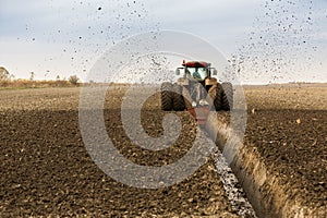 Tractor with double wheeled ditcher digging drainage canal