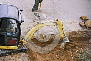 Tractor excavator and a man with a shovel dig a hole. manual and machine labor concept