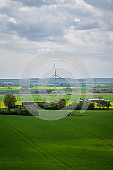 Tractor in farm field in front of a wind turbine generating clean energy in SkÃ¥ne Sweden