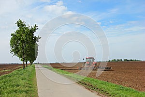 Tractor on a farm field working with a disc harrow